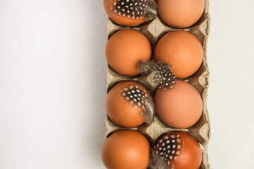Homemade fresh eco eggs in paper packaging with quail feathers. Top view, space for text.