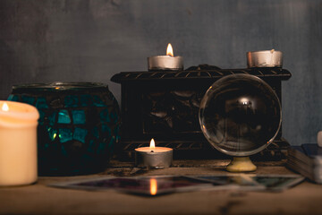 Close-up of a tarot card arrangement with a crystal ball and flickering candles on an aged wooden surface.
