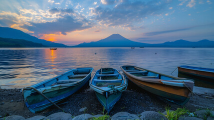 Three small row boats on the shore of Mount Fuji at Lake Yamanaka, during sunset with beautiful...