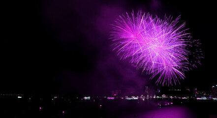 Spectacular purple colored fireworks exploding in to the night sky over the bay