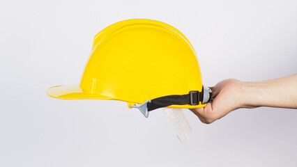 Hand is hold yellow SAFETY HELMET on white backround.