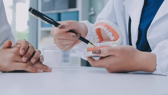 Happy smiling Asian female dentist doctor examining teeth model diagnosing patient dental hygiene using tablet x-ray technology, healthcare expert orthodontist specialist hospital meeting office room