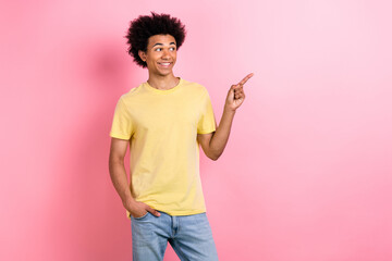 Photo of nice young man look point finger empty space wear yellow t-shirt isolated on pink color...