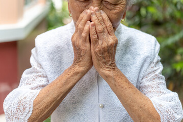 Senior Asian women use to hands to closing her mouth  unwell coughing with sore throat...