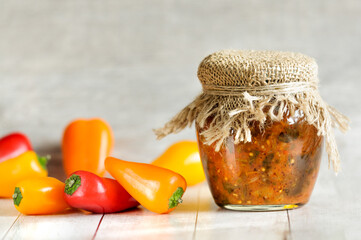 Jar with homemade salad and sweet paprika fruits on a gray wooden background. Natural lighting with copy space