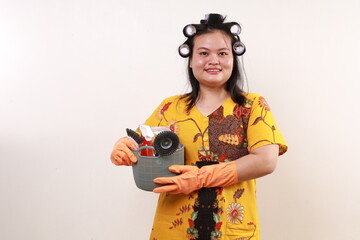Happy asian housekeeper standing while holding cleaning tools