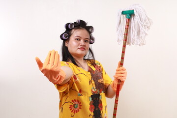 Confident asian housekeeper woman holding a mop while showing invitation or challenge hand gesture