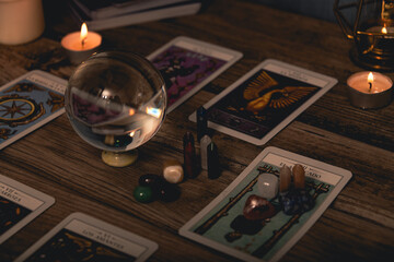 Tarot cards including The Fool and The Lovers alongside crystals and candles on a textured wooden table.