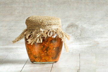 Homemade Lecho Salad in a glass jar on a gray wooden background. Place for text. Copy space. Home canned vegetables