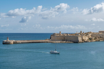 A boat enters Valletta Bay passing near the Ricasoli East Breakwater, Kalkara, Malta