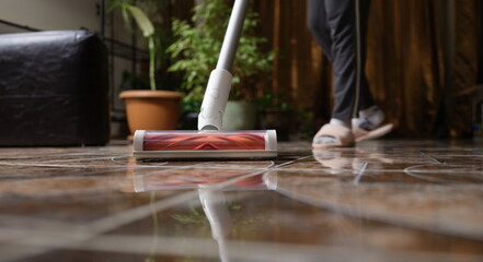 Cordless vacuum cleaner with turbo brush cleans tiles in living room. Modern home cleaning...