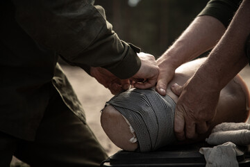 Ukrainian soldiers train to apply a bandage on a dummy wounded leg