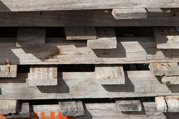 Background of old wooden pallets stacked on top of each other in outdoor environment. Wooden planks close up, texture