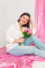 Happy woman smiling while cradling a bunch of delicate pink tulips,. Feminine, soft, beautiful, delicate, brunette, spring.