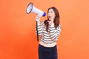 Asian woman candid screaming expression standing holding megaphone loudspeaker for warning while...