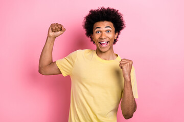 Photo of lucky excited guy dressed yellow t-shirt looking shouting rising fists isolated pink color...