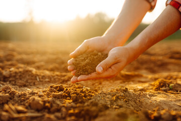 Farmer's hands holding soil, checking soil health before sowing. Ecology, agriculture concept.