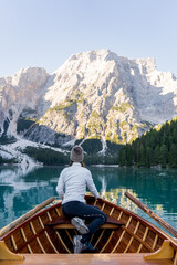 white woman sitting in wooden boat enjoying the views of lago di braies