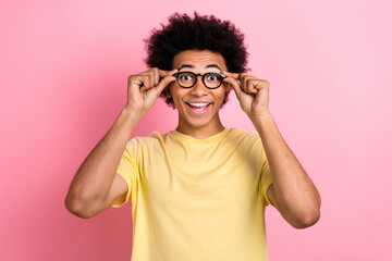 Portrait of astonished cheerful man toothy smile hands touch glasses beaming smile isolated on pink color background