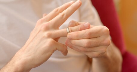 Close-up of hand removing wedding ring, symbolizing union dissolution. Emotional separation...