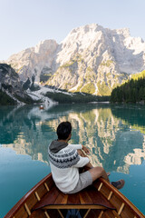 White man sitting in wooden boat enjoying the views of Lago di Braies, Dolomites. Italy 