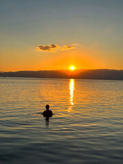 Person Swimming in Water at Sunset