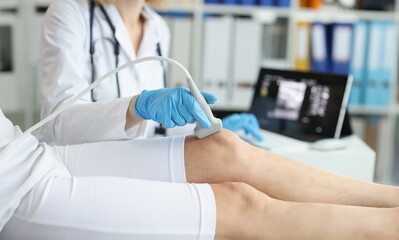 Orthopedic doctor makes ultrasound examination of tpatient knee in clinic. Medical research and...