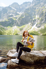 Happy woman feeling happy among amazing mountains, forest and lake, enjoy the nature landscape. Lifestyle, traveler, nature, active life.