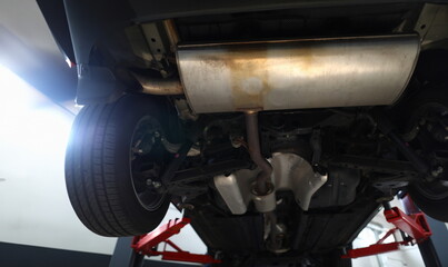Bottom of car with muffler on lift. Car suspension service concept © H_Ko