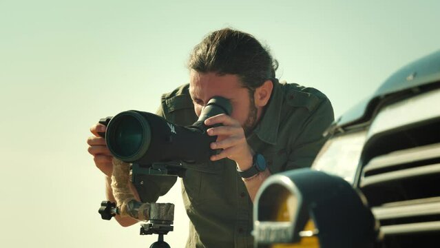 Man using telescope for bird and animal watching in nature.