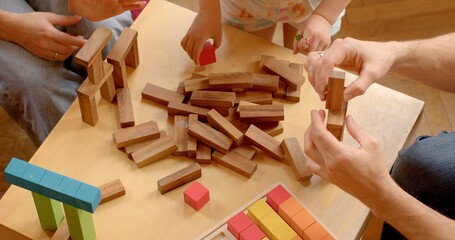 Close-up of parents with kids enjoy quality time together in child's room, building with blocks....