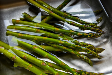 Asparagus soaking in water  in sink prior to additional preparation an cooking.
