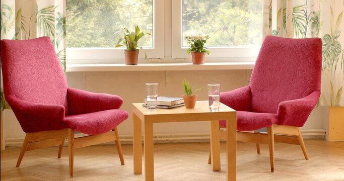 Two empty chairs in sunny office of psychotherapist. No people. Bright, welcoming space for therapy sessions. Calm and tranquility, peaceful environment conducive to introspection and healing. 