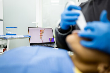 An unrecognizable dentist uses an intraoral scanner to obtain 3D digital impressions of a patient's...