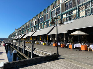Apartments in rows near a marina dock. Buildings and a quay in a harbour district. Street and boardwalk in a port city.