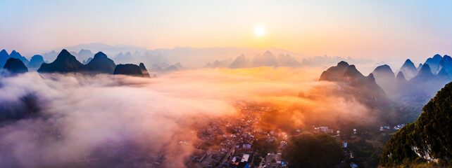 Panorama of sea of clouds around mountain peaks at sunrise. Famous karst mountain natural landscape...