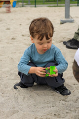 Kid male play in sand on playground with toys