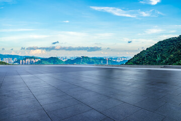 Empty square floor and green mountains with city skyline in the morning