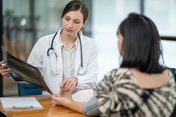 A doctor discusses chest X-ray results with her patient, explaining the health findings in a clear...