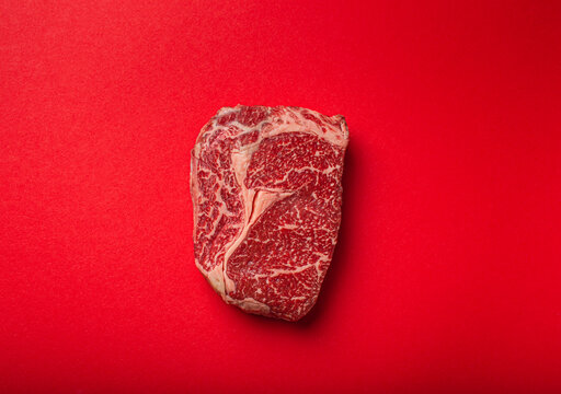 Raw Ribeye on red background