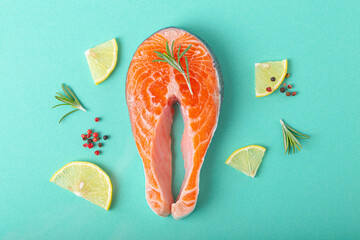 Raw fresh fish salmon steak top view on blue background with rosemary, lemon wedges and spices