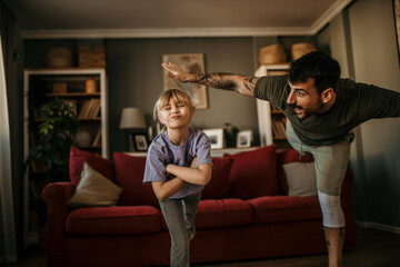Father and his daughter balancing together on one leg during a home workout - obrazy, fototapety, plakaty
