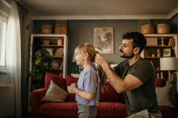 Father fixing his little girl's hair, preparing for a home workout