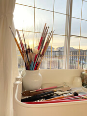 Paint brushes, spatula and artist material in a studio with outdoor view. Art supplies. Creative tools in a mobile cart.