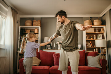 Dad and daughter exercising together in casual sportswear in their contemporary living space