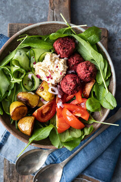 Cucumber and spinach salad with beetroot falafel, hummus and roast potatoes