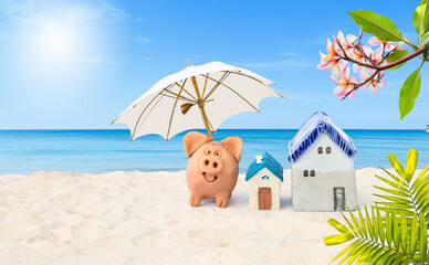 Miniature house with piggy bank under beach umbrella on tropical beach, real estate and property business concept