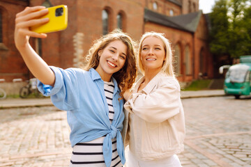 Happy women taking selfie while walking down the street. Fashion, travel, technology, blogging...