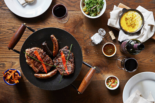 Grilled beef stea and sausages with baked cheese, salad and red wine