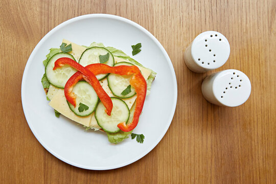 A open sandwich of cheese, cucumber, peppers and lettuce